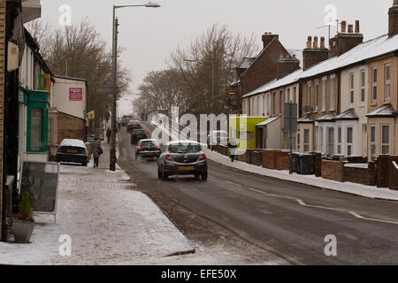 Journée enneigée sur Mill Road, une rue animée avec voitures et piétons marchant sur le sentier de pied. Cambridge, Angleterre, Royaume-Uni Banque D'Images