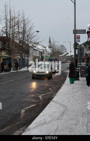 Journée enneigée sur Mill Road, une rue animée avec voitures et piétons marchant sur le sentier de pied. Cambridge, Angleterre, Royaume-Uni Banque D'Images