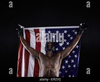Jeune comptable boxer drapeau américain soulevé dans la victoire sur fond noir. Champion de boxe américain des succès à célébrer. Banque D'Images