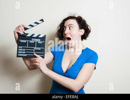 Fille en bleu t-shirt avec drôle stupéfait face montrant movie clapper sur fond blanc Banque D'Images