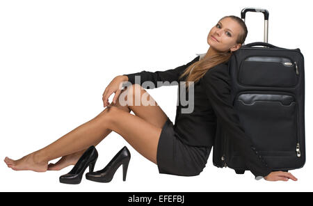 Businesswoman with her chaussures assis main reposant sur le sol, à côté d'valise vue avant Banque D'Images