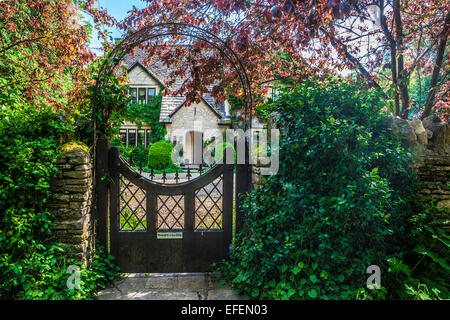 Vue à travers la porte du jardin d'une maison de campagne dans les Cotswolds dans le Wiltshire. Banque D'Images