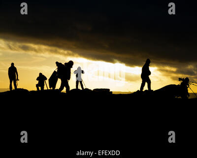 Groupe de photographes avec trépieds silhouette sur le coucher du soleil à Curbar Edge dans Parc national de Peak District Derbyshire UK Banque D'Images