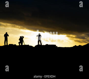 Groupe de photographes avec trépieds silhouette sur le coucher du soleil à Curbar Edge dans Parc national de Peak District Derbyshire UK Banque D'Images