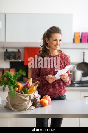 Portrait of happy young housewife holding grocery shopping vérifie Banque D'Images