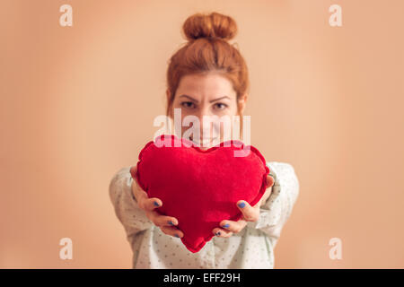 Belle jeune femme offrant un coeur, couleurs rétro Banque D'Images