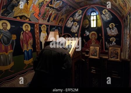 Un homme embrasse une icône religieuse à l'intérieur de la richement décorée 'ParekkLESION des trois,' chapelle dédiée aux trois grands évêques Saint Basil le Grand, Saint Grégoire le théologien, Et Saint-Jean Chrysostom dans le monastère orthodoxe grec Saint Varlaam construit en 1541 sur des piliers de grès naturel, à Meteora à la limite nord-ouest de la plaine de Thessaly près de la rivière Pineios et des monts Pineos, dans le centre de la Grèce Banque D'Images