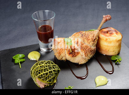 Confit de canard farci aux canneberges et boule de chou suédois le fondant et la sauce groseille rouge sur une plaque en ardoise Banque D'Images