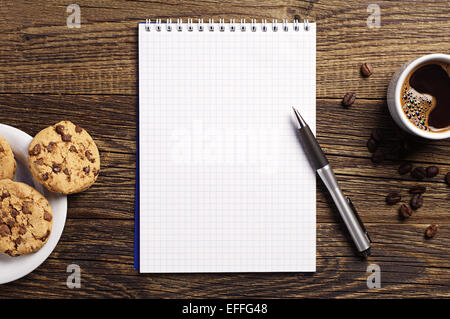 Ouvrir le bloc-notes et tasse de café avec des biscuits au chocolat sur vintage table en bois. Vue d'en haut Banque D'Images