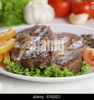 Les côtelettes de porc steaks de viande avec des frites et salade on plate Banque D'Images