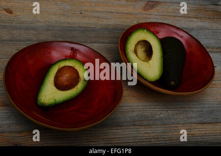 Avocat en deux Bol en céramique rouge sur une table en bois Banque D'Images