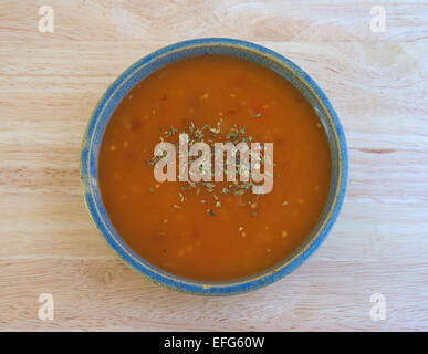 Vue de dessus d'un bol de soupe de tomates aux herbes menthe en biscuit avec assaisonnement sur une table en bois. Banque D'Images