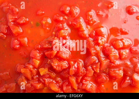 Fermer la vue de dés de tomates au jus de tomates avec piment jalapeño ajouté illuminée par la lumière de la fenêtre naturelle. Banque D'Images