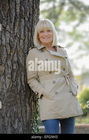 Portrait of a smiling woman leaning on a tree Banque D'Images