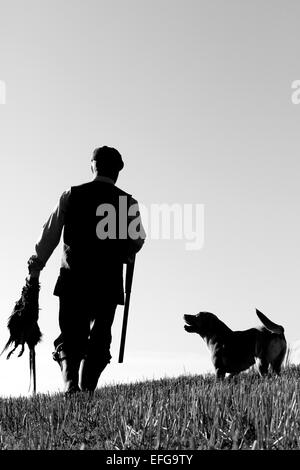 Garde-chasse avec chien exerçant son fusil et les faisans, silhouette noir et blanc Banque D'Images