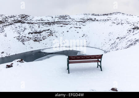 La caldeira de Kerid rocheux (ou Kerith) volcan et lac de cratère gelés en Islande, une destination touristique populaire, en hiver au cours d'une averse de neige Banque D'Images