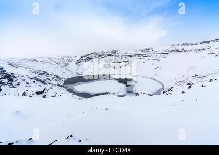 La caldeira de Kerid rocheux (ou Kerith) volcan et lac de cratère gelés en Islande, une destination touristique populaire, en hiver au cours d'une averse de neige Banque D'Images