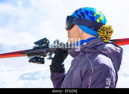 Vue latérale du skieur beau homme portant masque et la tenue en main, équipement de ski s'amuser sur les montagnes Banque D'Images