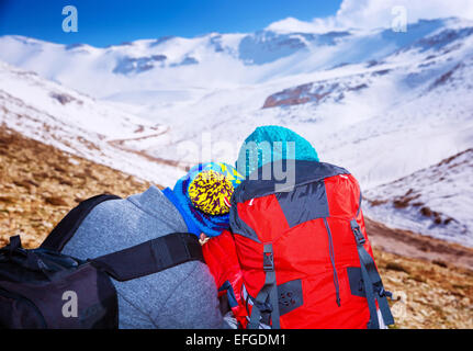 Couple heureux, les voyageurs appréciant snowy view, assis en haut de la Montagne, vacances d'hiver extrême romantique, style de vie actif Banque D'Images