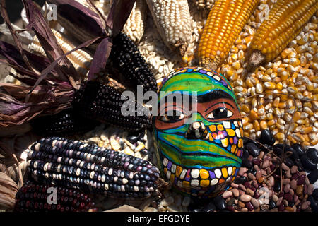 Un masque de couleur décore une table pleine d'épis de maïs de semence Tepetlixpa 'Banque', créé par Tomas Villanueva Buendia 'Tomaicito» Banque D'Images