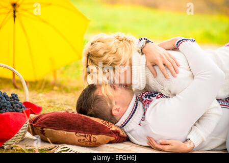 Kissing couple sur le plaid en automne park Banque D'Images