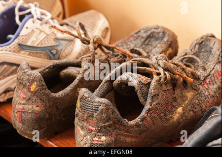 Chaussures de course boueux humide recouvert de boue de la formation pays montrant les détails et lacets Matériau imperméable Banque D'Images