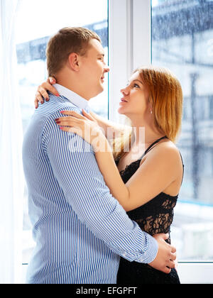 Senior couple in front of window embrasser Banque D'Images