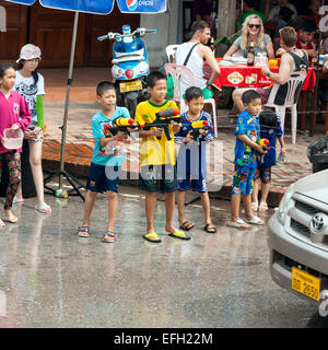 Petits garçons profiter les gens avec canon à eau pendant la célébration du Nouvel An Lao et fête de l'eau dans la région de Luang Prabang. Banque D'Images