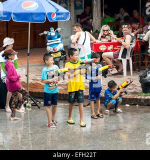 Petits garçons profiter les gens avec canon à eau pendant la célébration du Nouvel An Lao et fête de l'eau dans la région de Luang Prabang. Banque D'Images