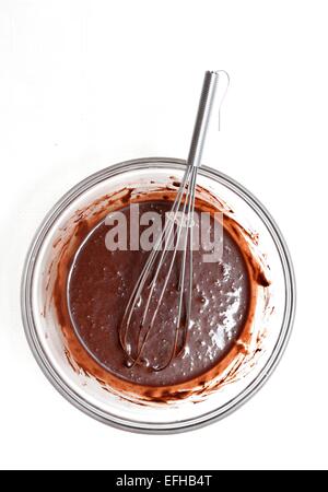 Le mélange d'une pâte de chocolat dans un bol en verre pour faire un gâteau. Banque D'Images