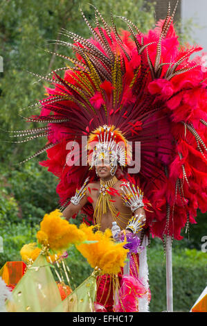 Carnaval d'hommes portant une coiffe élaborée interprète de plumes rouges sur un flotteur dans la procession, le carnaval de Notting Hill, Londres, Angleterre, Royaume-Uni Banque D'Images