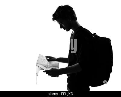 Jeune homme backpacker reading map silhouette en studio isolé sur fond blanc Banque D'Images