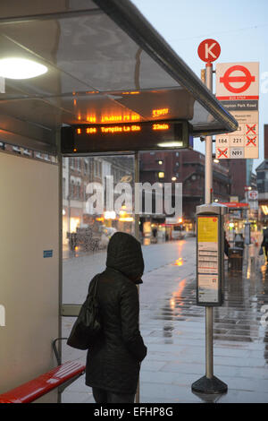 Turnpike Lane, Londres, Royaume-Uni. 5e février 2015. Une femme à un arrêt de bus qui indique un 23 minutes d'attente jusqu'à ce que le prochain bus à Turnpike Lane le premier jour de trois grèves des chauffeurs de bus de Londres sur les écarts de rémunération entre les entreprises. Crédit : Matthieu Chattle/Alamy Live News Banque D'Images