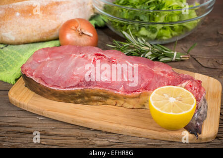 Steak cru barbue sur une planche à découper sur la vieille table en bois Banque D'Images