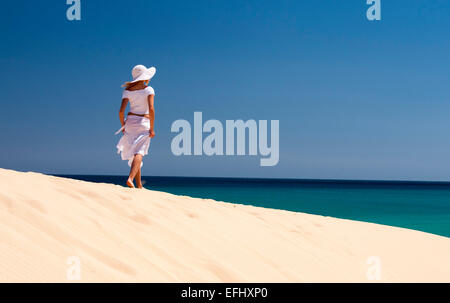 Jeune femme avec chapeau marchant le long d'une dune de sable, Playa de Sotavento, Sotavento, Costa Calma, Jandia, Fuerteventura, Fuerteventura, Banque D'Images
