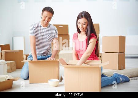 Jeune couple unpacking boxes dans leur nouvel appartement Banque D'Images