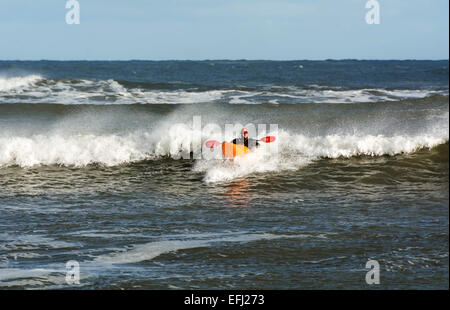 Un homme d'eau vive canoë kayak court grâce à de grosses vagues. Banque D'Images