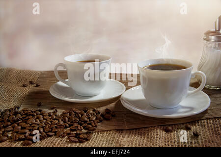 Deux tasses de café fumant, les grains de café à l'avant Banque D'Images