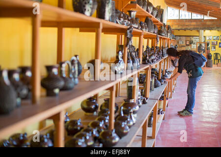 San Bartolo Coyotepec, Mexique - Un visiteur regarde au-dessus de poterie noire en vente au studio créé par Rosa du vrai Mateo de Nieto Banque D'Images