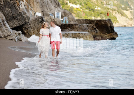 Happy young couple en train de marcher sur la plage de Positano à wedding day Banque D'Images