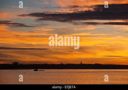 Le lever du soleil sur le fleuve Amazone à 6h avec bien river bank silhouetted against orange rouge et jaune spectaculaire matin aube Banque D'Images