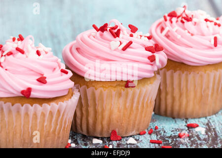 Pink Valentines Day cupcakes avec sprinkles on blue background vintage en bois Banque D'Images