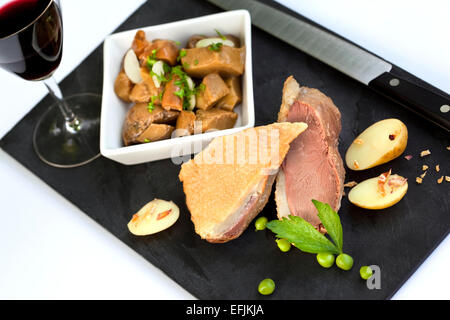 Confit de canard, les champignons et les pommes de terre sur une ardoise Banque D'Images