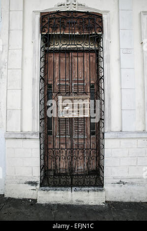 Cage à oiseaux en bois étendus dehors sur la fenêtre en fer forgé décoratif grill avec un oiseau noir et blanc à l'intérieur, Cienfuegos, Cuba Banque D'Images