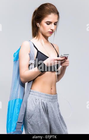 Belle femme sportive à l'aide de blackberry sur fond gris Banque D'Images