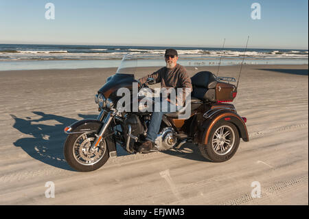 Un homme jouissant d'une tour sur le rivage de Daytona Beach avec sa moto Trike Harley Davidson Banque D'Images