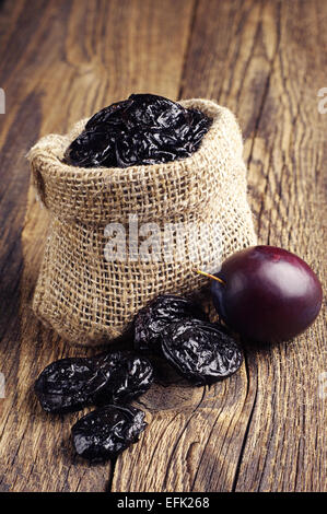 Les pruneaux avec les prunes en petits sac sur table en bois vintage Banque D'Images