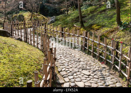 Jardin de Ritsurin-koen, Takamatsu, Japon. Un chemin traditionnel fait de pavés et bordé de clôtures basses en bambou Banque D'Images