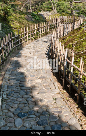 Jardin de Ritsurin-koen, Takamatsu, Japon. Un chemin traditionnel fait de pavés et bordé de clôtures basses en bambou Banque D'Images