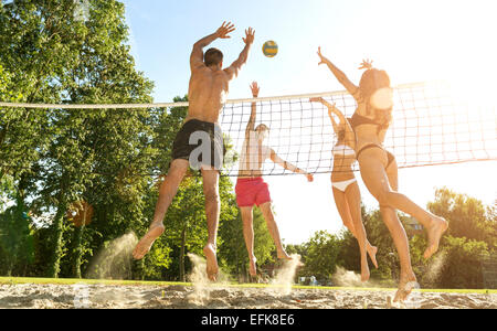 Groupe de jeunes amis jouer au volley-ball sur plage Banque D'Images